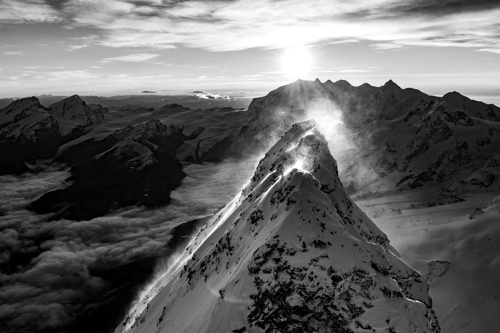 Grat mit wehender Schneefahne, die Sonne direkt dahinter, Schwarzweiss – Matterhorn